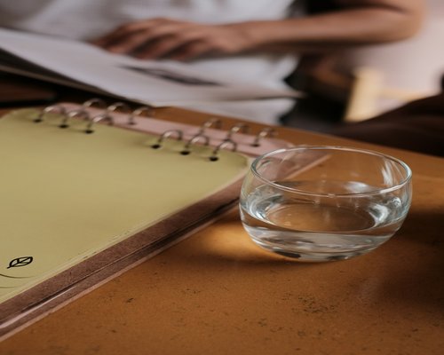 A notebook and a glass of water on a clean wooden desk